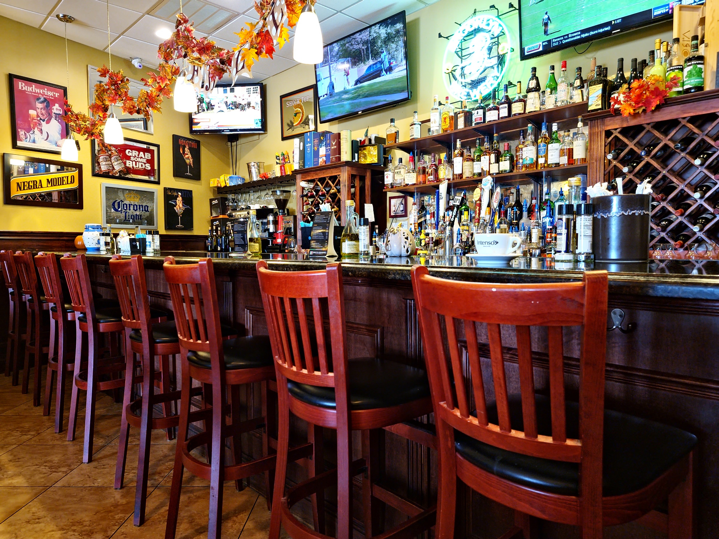 The bar with stools and a wall of bottles
