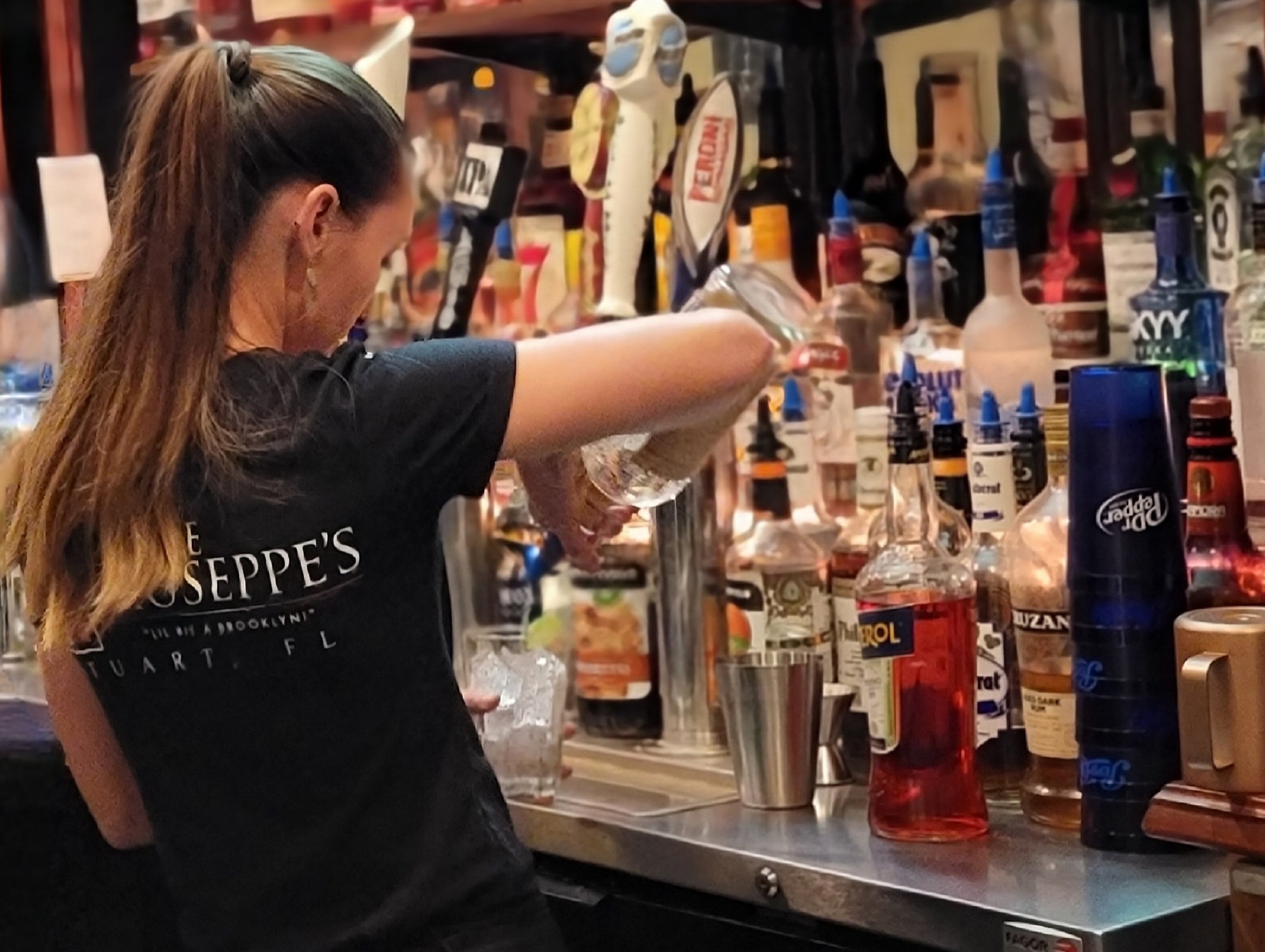 A bartender pouring a cocktail behind the bar