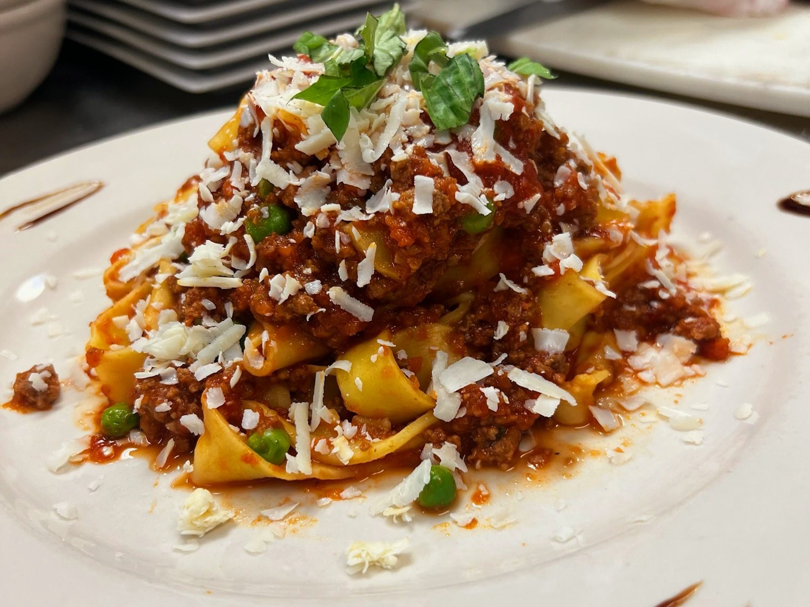 Fresh-made pappardelle piled high with hearty Bolognese, sweet peas and shaved cheese